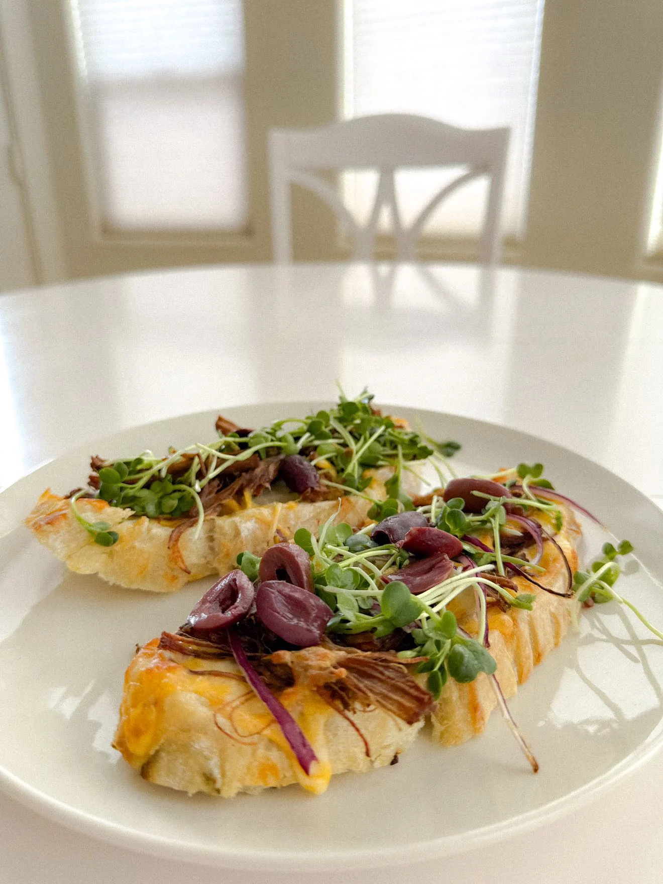 Two open-faced sandwiches generously topped with microgreens