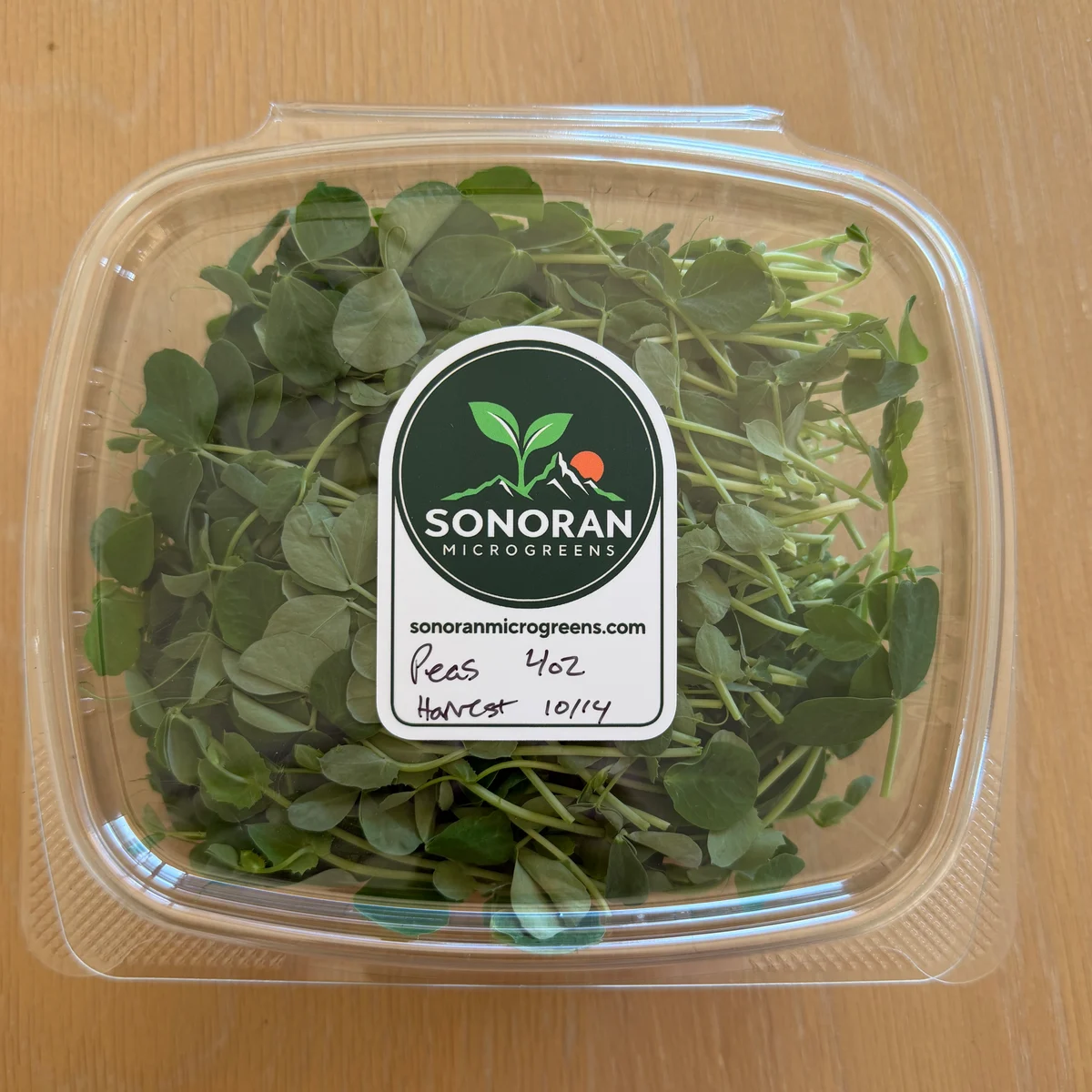 Fresh pea shoots in a labeled four-ounce container